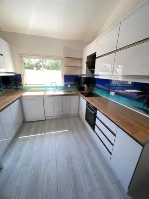 a kitchen with white cabinets and a wooden floor at Villa familiale climatisée, proche plage & lacs in Port-la-Nouvelle