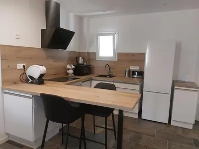 a kitchen with a wooden table and a refrigerator at La Parenthèse in Moussan