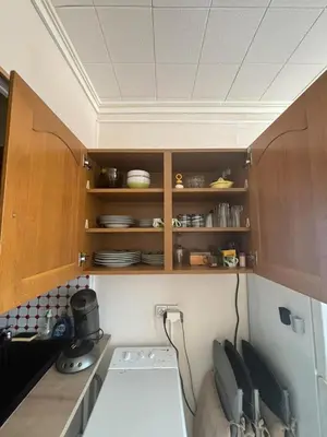 a kitchen with wooden cabinets and plates on shelves at L'Arbousier in Port-la-Nouvelle