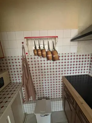 a kitchen with copper utensils on a tiled wall at L'Arbousier in Port-la-Nouvelle