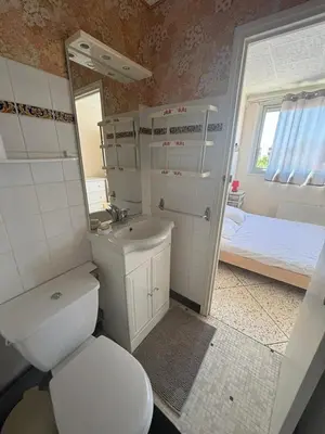 a bathroom with a toilet and a sink and a bed at L'Arbousier in Port-la-Nouvelle