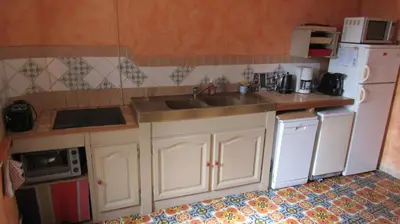 a kitchen with white cabinets and a sink and refrigerator at Maison Minervoise in Aigne