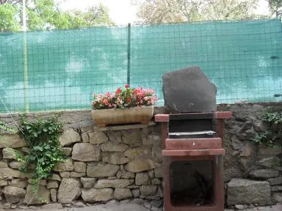 a stone wall with a chair and a pot of flowers at Maison Minervoise in Aigne