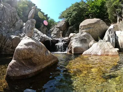 a pool of water with rocks and a waterfall at Maison Minervoise in Aigne