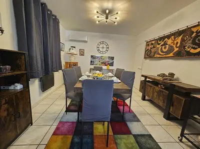 a dining room with a table and chairs and a clock at La Casa D'Eole YourHostHelper in Narbonne