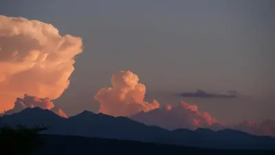 a sunset with clouds and mountains in the background at Maison avec vue sur le Lac de Montbel in Montbel