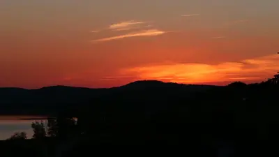 a sunset with the sun setting over the mountains at Maison avec vue sur le Lac de Montbel in Montbel