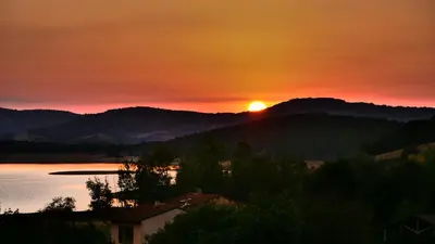 a sunset with the sun setting on a mountain at Maison avec vue sur le Lac de Montbel in Montbel