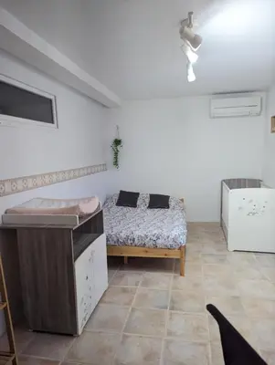 a bedroom with a bed in the corner of a room at Chambre climatisée 2 places plus une place Bébé 0-3 ans, salle de bain et WC en espace privatif in La Livinière