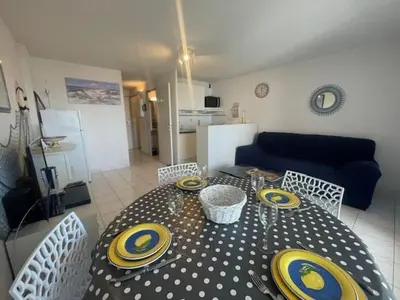 a dining room table with yellow and blue plates on it at 150 MARINA BAY CAP D'AGDE Quartier Falaises proche plage T2 cabine avec place de parking et piscine in Laure-Minervois
