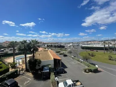 a view of a street with cars parked in a parking lot at 150 MARINA BAY CAP D'AGDE Quartier Falaises proche plage T2 cabine avec place de parking et piscine in Laure-Minervois