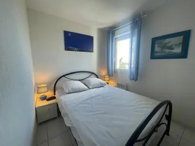 a bedroom with a bed and a window and two lamps at 150 MARINA BAY CAP D'AGDE Quartier Falaises proche plage T2 cabine avec place de parking et piscine in Laure-Minervois