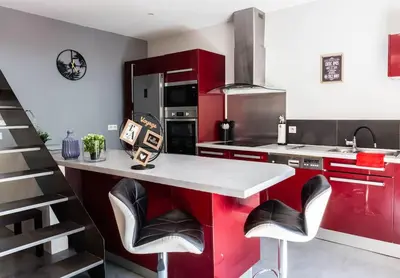 a kitchen with red cabinets and black appliances at Duplex moderne centre Narbonne in Narbonne