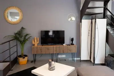 a living room with a tv and a staircase at Duplex moderne centre Narbonne in Narbonne