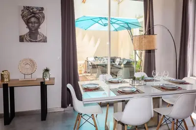 a dining table with white chairs and a blue umbrella at Duplex moderne centre Narbonne in Narbonne