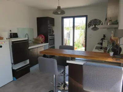 a kitchen with a wooden table and some chairs at L'hibiscus in Narbonne