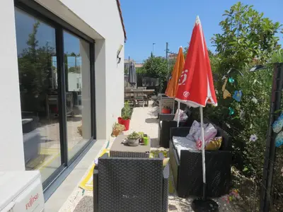 a patio with a table and a red umbrella at L'hibiscus in Narbonne
