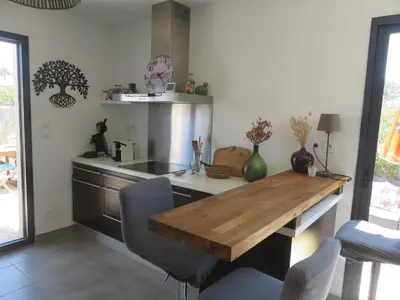a kitchen with a wooden table and a counter at L'hibiscus in Narbonne