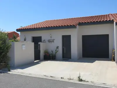 a white house with two garage doors at L'hibiscus in Narbonne