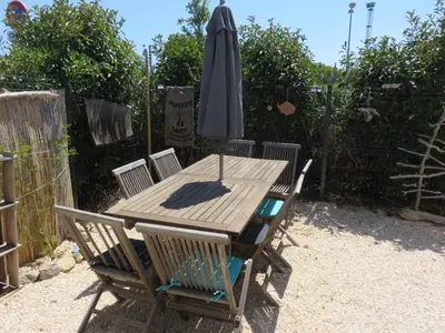 a wooden table with an umbrella and two chairs at L'hibiscus in Narbonne