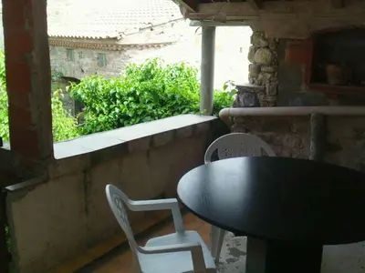 a table and chairs on a balcony with a window at Petit gite rustique et économique in Albas