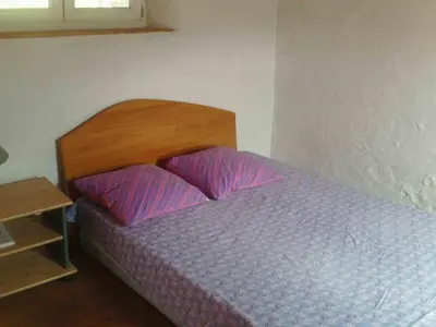 a bedroom with a bed with a wooden headboard and two pillows at Petit gite rustique et économique in Albas