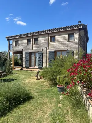 a house with a yard with flowers in front of it at Cottage atypique avec piscine & accès au lac 6 personnes in Molleville
