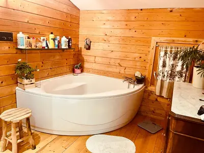 a white tub in a room with wooden walls at Cottage atypique avec piscine & accès au lac 6 personnes in Molleville