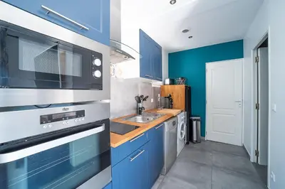 a kitchen with blue cabinets and a sink at Casa Sacha - Appt avec piscine partagée in Fitou