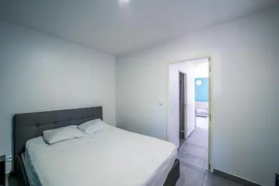 a white bedroom with a bed and a hallway at Casa Sacha - Appt avec piscine partagée in Fitou