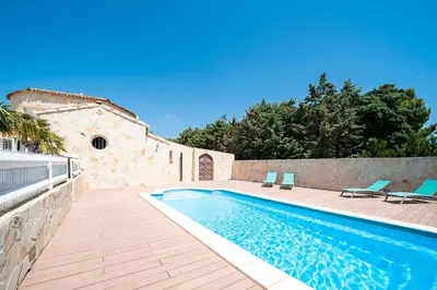 a swimming pool with two chairs and a building at Casa Jade - Appt pour 4 in Fitou