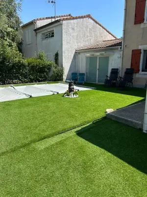 a child sitting on the grass in a yard at CARCASSONNE Studio avec Jacuzzi y piscina in Carcassonne