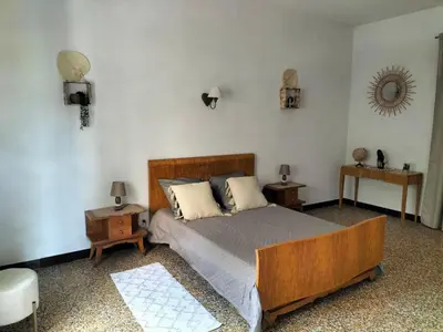 a bedroom with a bed with two night stands and two tables at Appartement le petit bonheur in Saint-Pons-de-Thomières