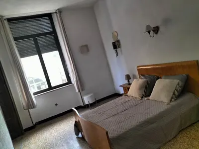 a bedroom with a bed and a large window at Appartement le petit bonheur in Saint-Pons-de-Thomières