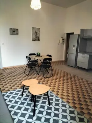 a room with a table and chairs and a kitchen at Appartement le petit bonheur in Saint-Pons-de-Thomières