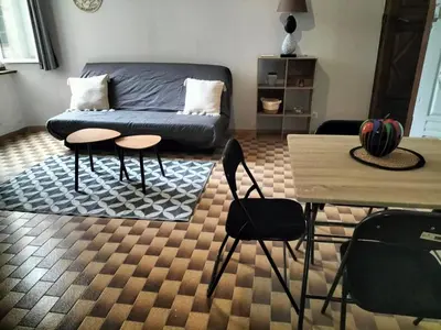 a living room with a couch and a table and chairs at Appartement le petit bonheur in Saint-Pons-de-Thomières