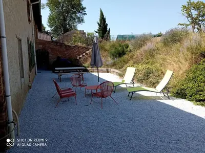 a group of chairs and a table and an umbrella at Maison Lauraguaise parking grand jardin wifi in Villenouvelle
