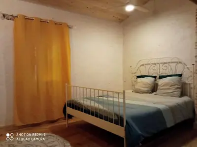 a bedroom with a bed with an orange curtain at Maison Lauraguaise parking grand jardin wifi in Villenouvelle