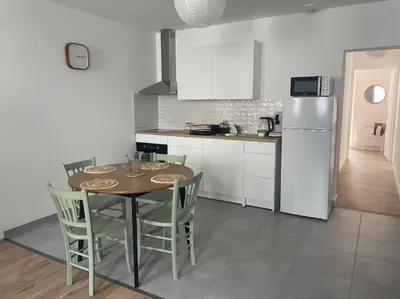 a kitchen with a table and chairs and a refrigerator at Le Bastide l 2 chambres l Rez-de-chaussée l Terrasse l Clim in Sémalens