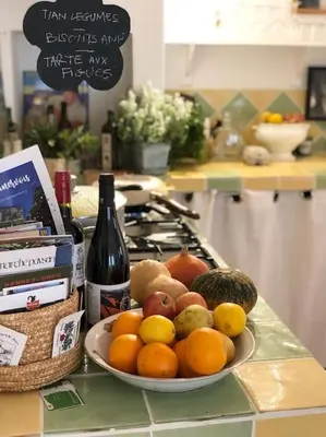 a plate of fruit on a counter with a bottle of wine at Superbe maison de village et sa terrasse panoramique in Oupia