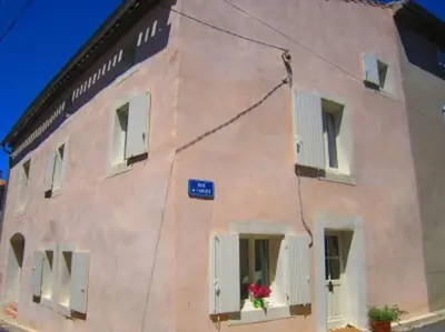 a pink building with white shutters and flowers on the windows at Superbe maison de village et sa terrasse panoramique in Oupia