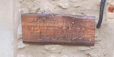 a wooden sign on the side of a wall at A L' Estiu in Latour-de-France