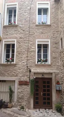 a stone building with two windows and a door at A L' Estiu in Latour-de-France