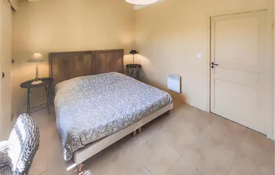 a bedroom with a bed and two tables and a door at Pet Friendly Home In Saint Laurent De La Ca in Saint-Laurent-de-la-Cabrerisse