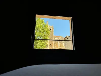 a window view of a building and a tree at Le Jardin de la Cathédrale - T2 - Centre Ville - Emplacement & Vue Extraordinaires in Narbonne