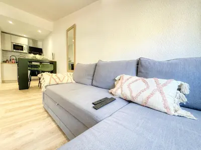 a living room with a blue couch with a remote control at Le Jardin de la Cathédrale - T2 - Centre Ville - Emplacement & Vue Extraordinaires in Narbonne