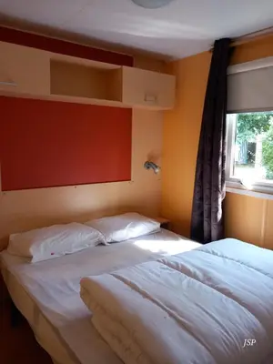 two beds in a room with a window at Mobil-home Riviera in Vaudreuille