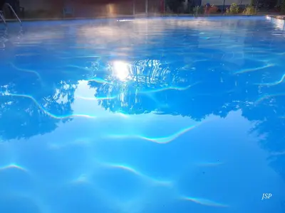 a pool of blue water with a light in it at Mobil-home Riviera in Vaudreuille