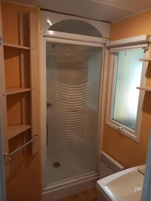 a glass shower in a bathroom next to a window at Mobil-home Riviera in Vaudreuille