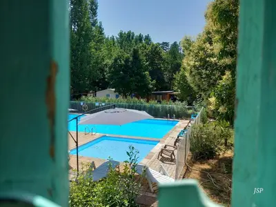 a swimming pool with an umbrella and some chairs at Mobil-home Riviera in Vaudreuille